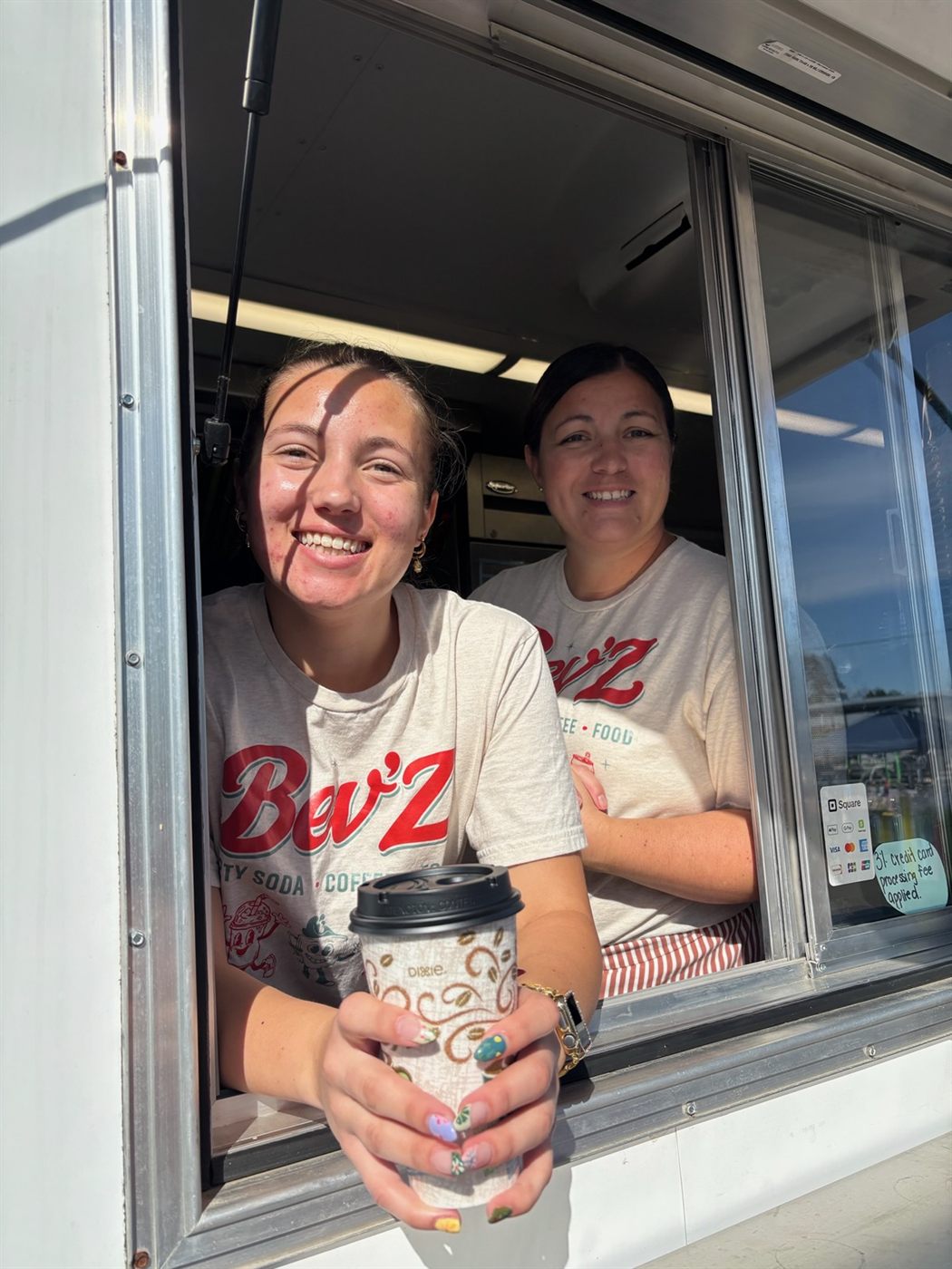 Bev'Z staff handing a coffee out the trailer's service window
