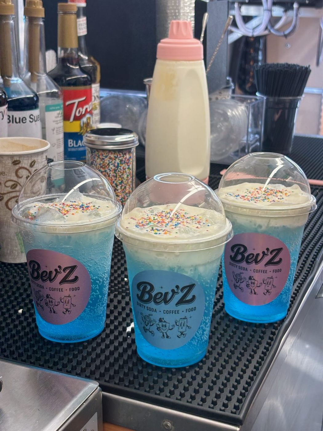Three blue slushies topped with whipped cream and rainbow sprinkles