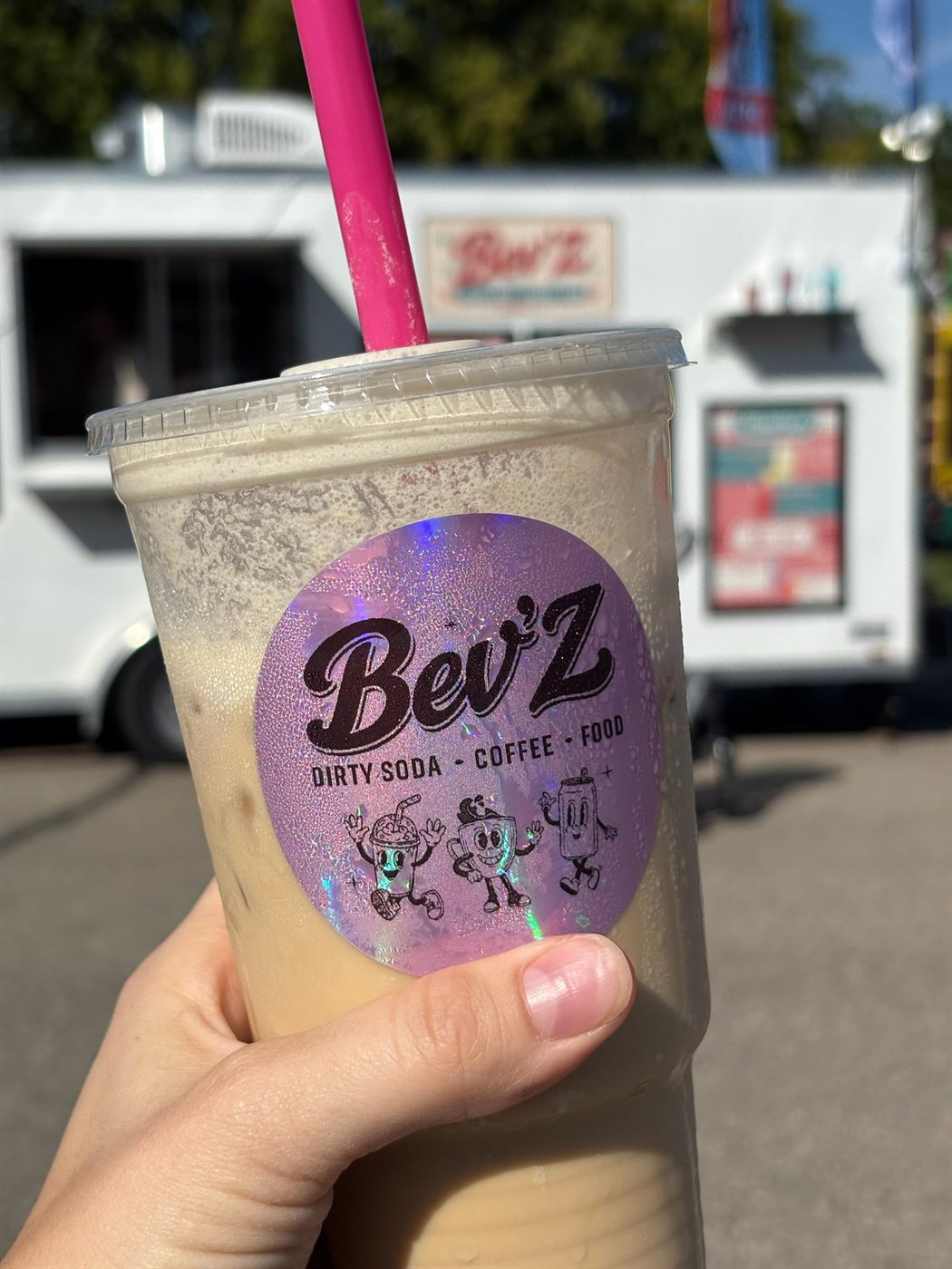 An iced Bev'Z drink in front of the trailer on a blue-sky day